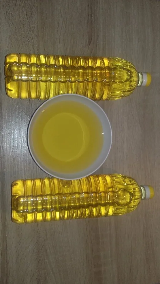 Two PET bottles of oil beside a glass of oil on a table